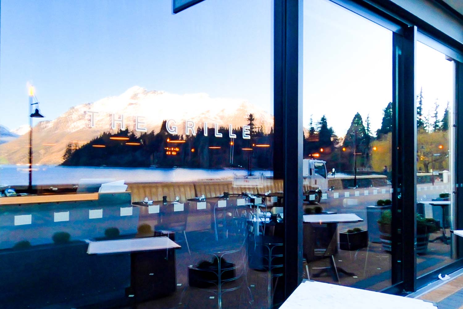 A reflection of snow capped mountains in a restaurant front glass window