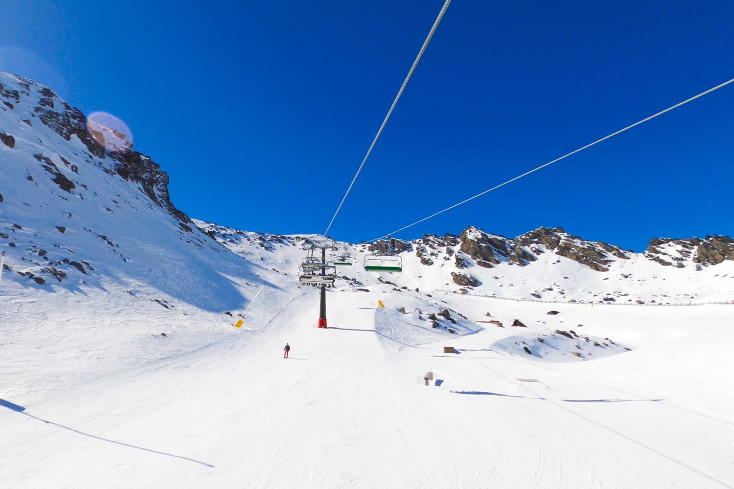 views of a chair lift and piste with blue skies overhead